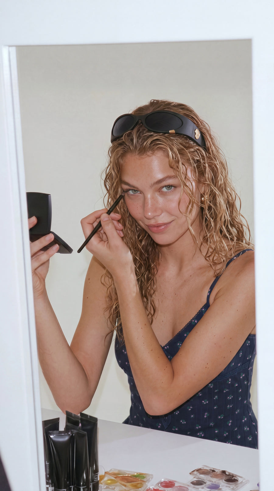 Model wearing innsol Cail Matt Black sunglasses as a headband while getting ready